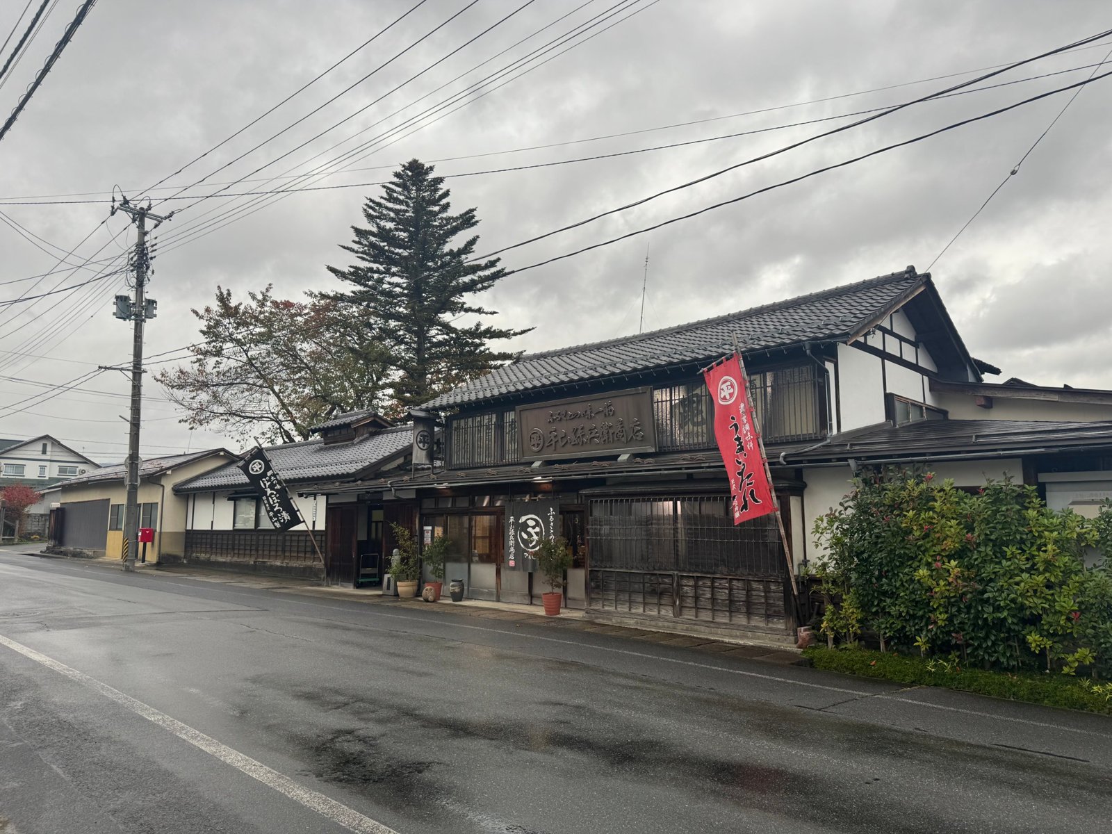 雨上がりの米沢の通り沿いに建つ、平山孫兵衛商店の木造の店構え
