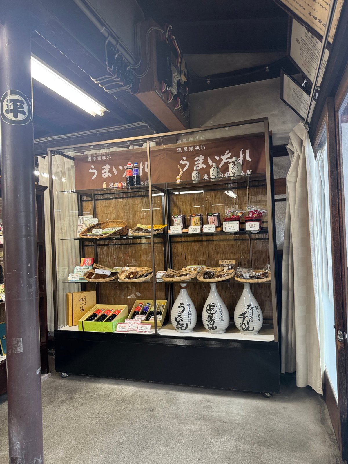 昔の「うまいたれ」の看板の下に、味噌や漬物、うまいたれのギフトが並ぶ棚